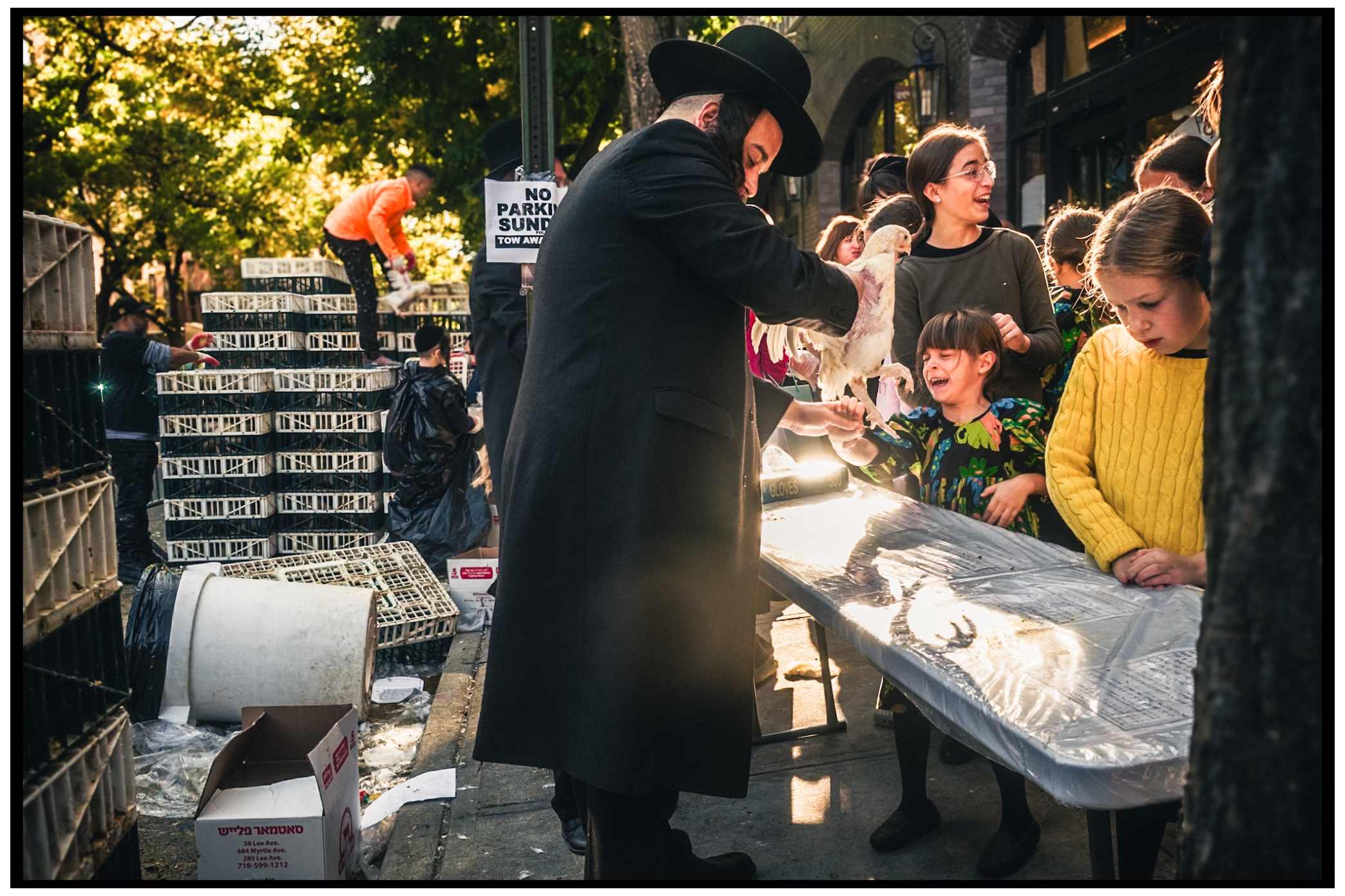 Group gathers around a table during an outdoor religious ceremony. Kapparot, Brooklyn NYC