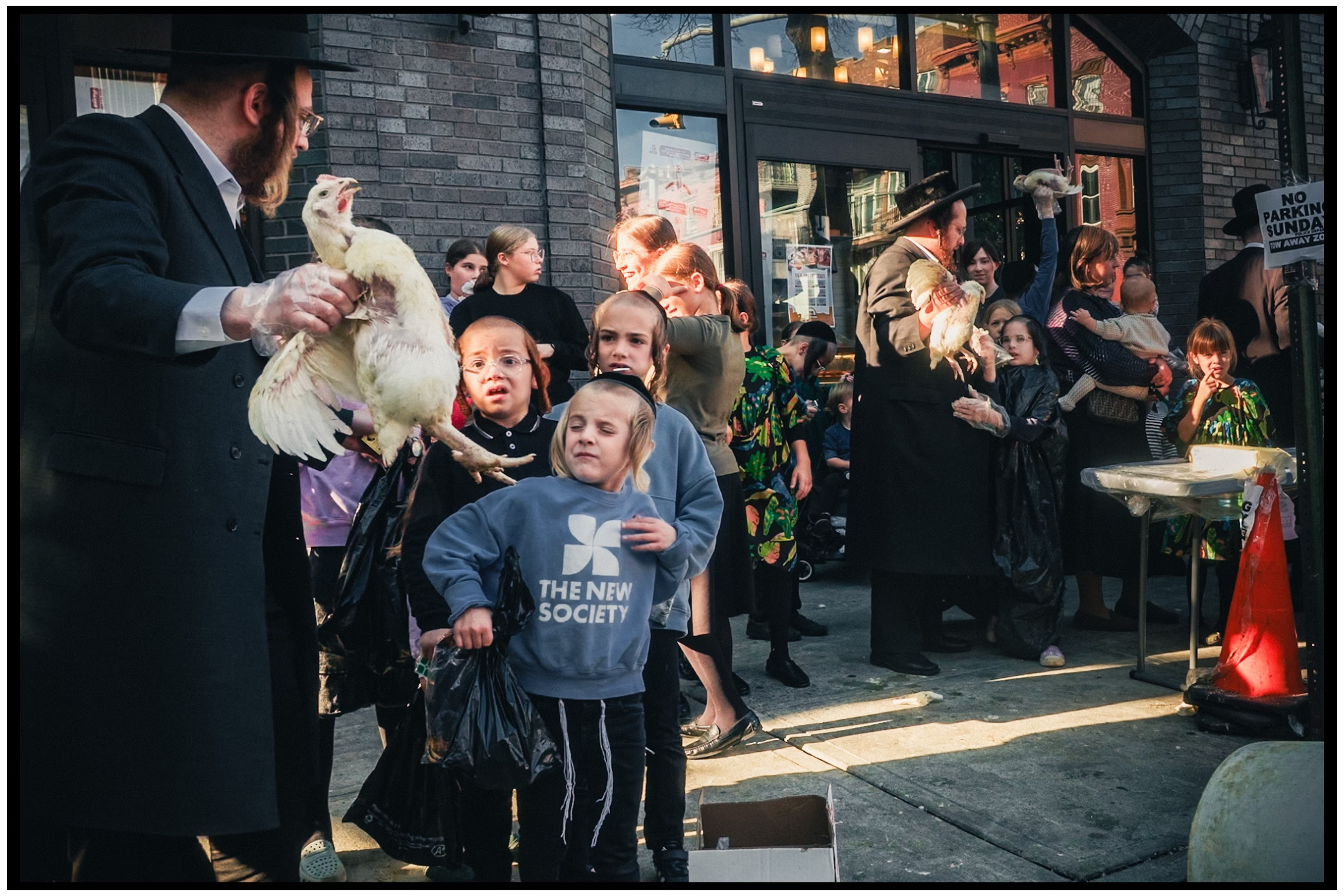 People gather outside a building during a traditional ceremony with chickens. Kapparot, Brooklyn NYC