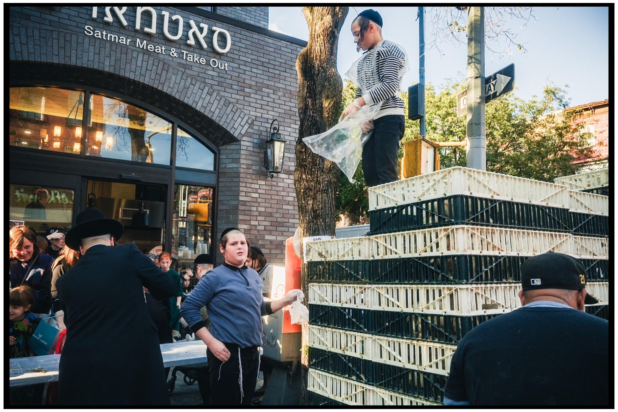 People gather near stacked cages outside a storefront during a ceremony. Kapparot, Brooklyn NYC