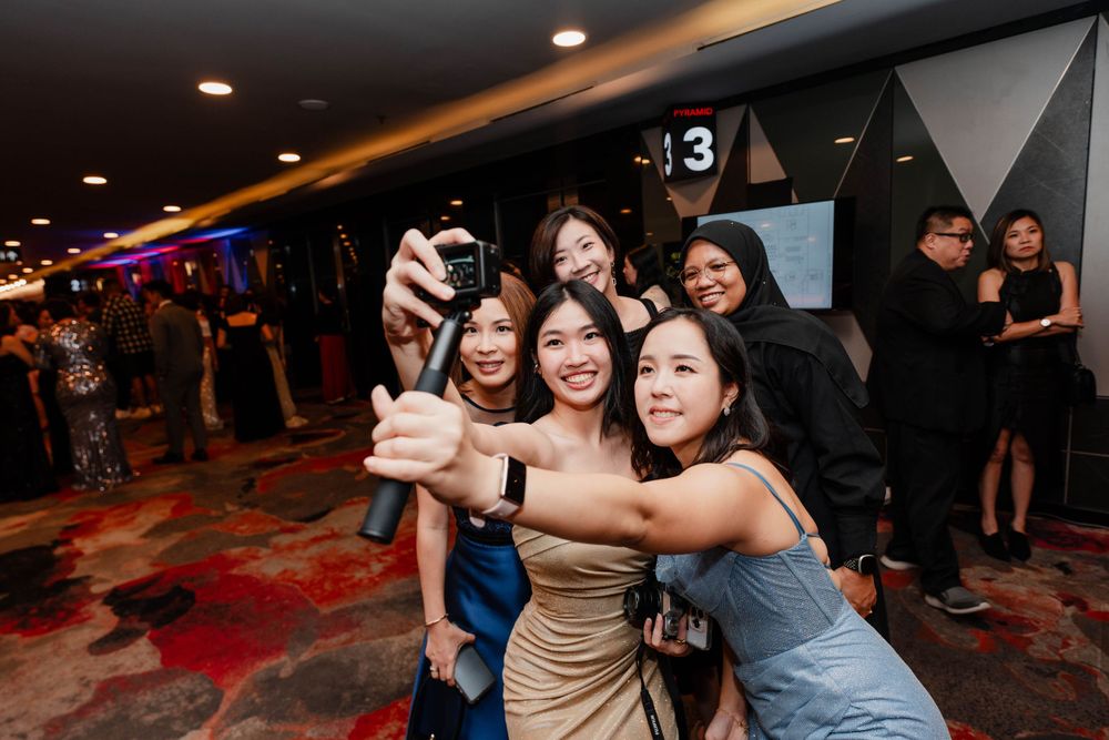 A group taking a fun selfie together at an indoor event with decorative geometric wall panels.