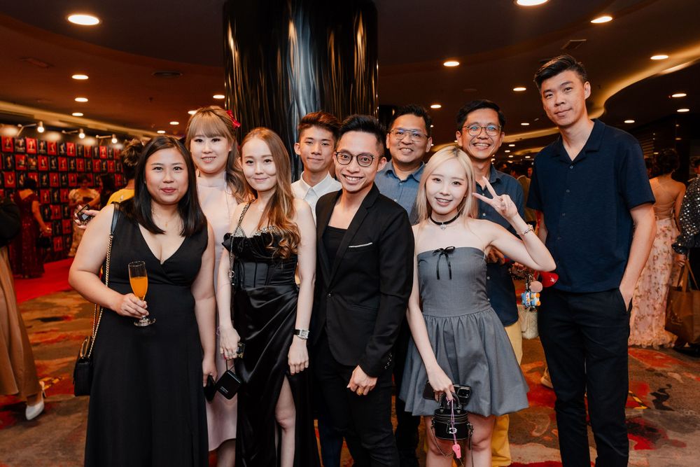 Group photo of attendees in formal black and gray attire at an indoor event venue.