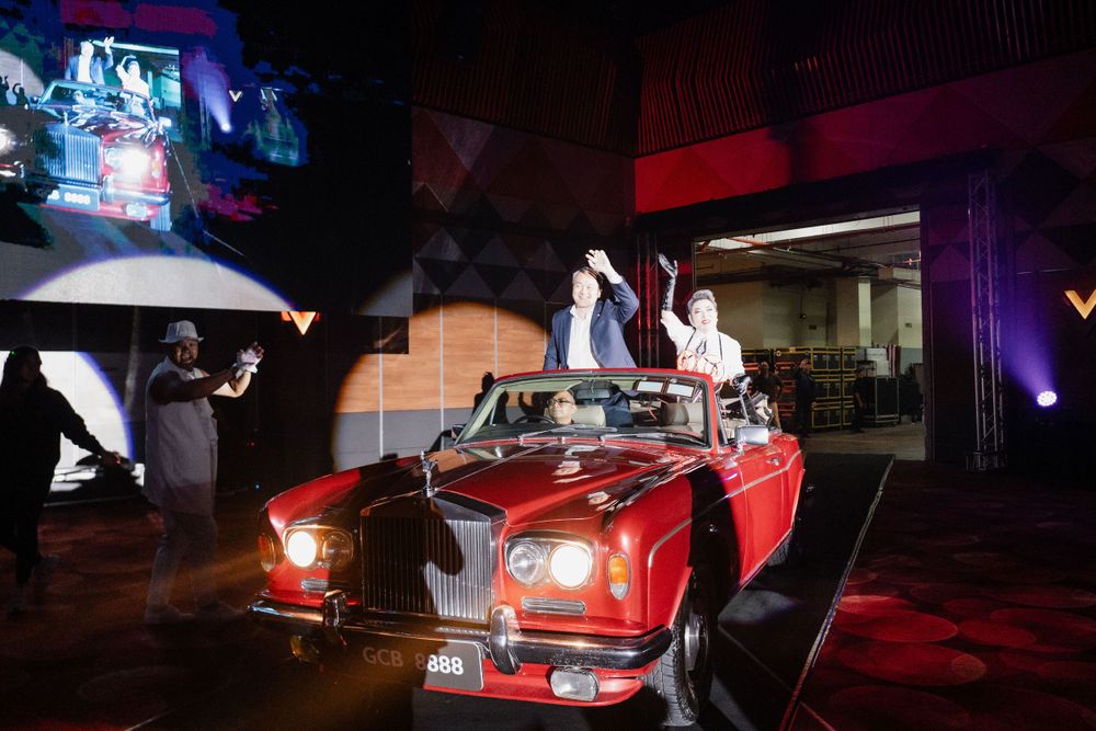 A classic red convertible car displayed indoors with dramatic lighting and projection effects.