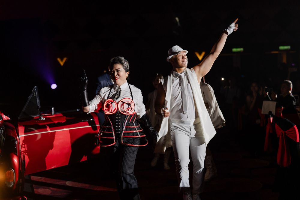 Two performers energetically dancing on a dark stage with dramatic red lighting effects.