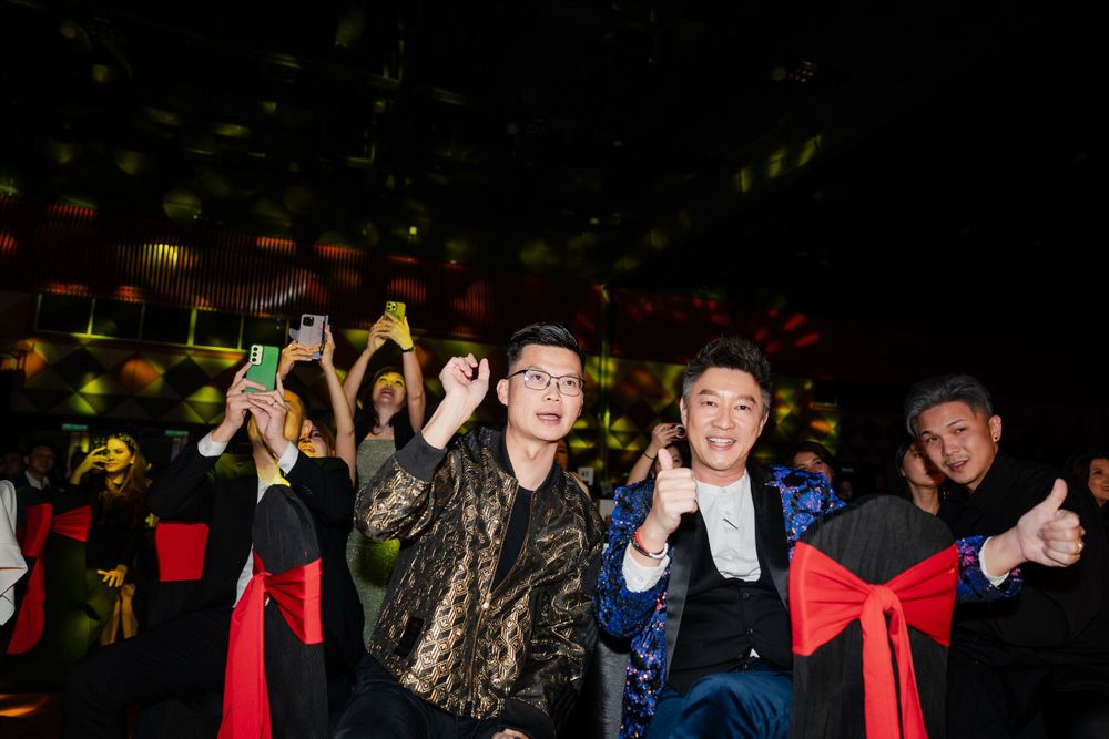 Excited attendees celebrating and posing at an event with red chair decorations.