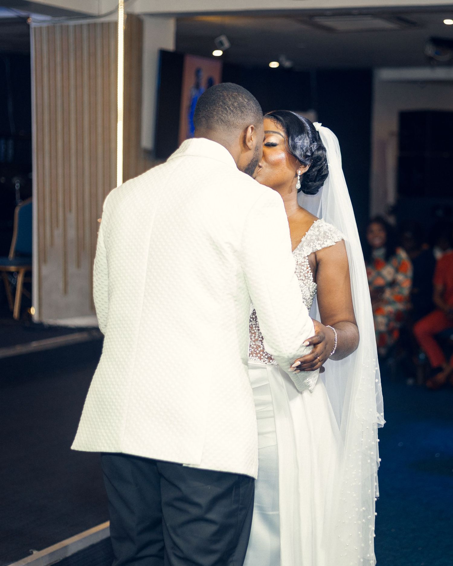 Tender moment between newlyweds embracing in white formal attire during their wedding ceremony.