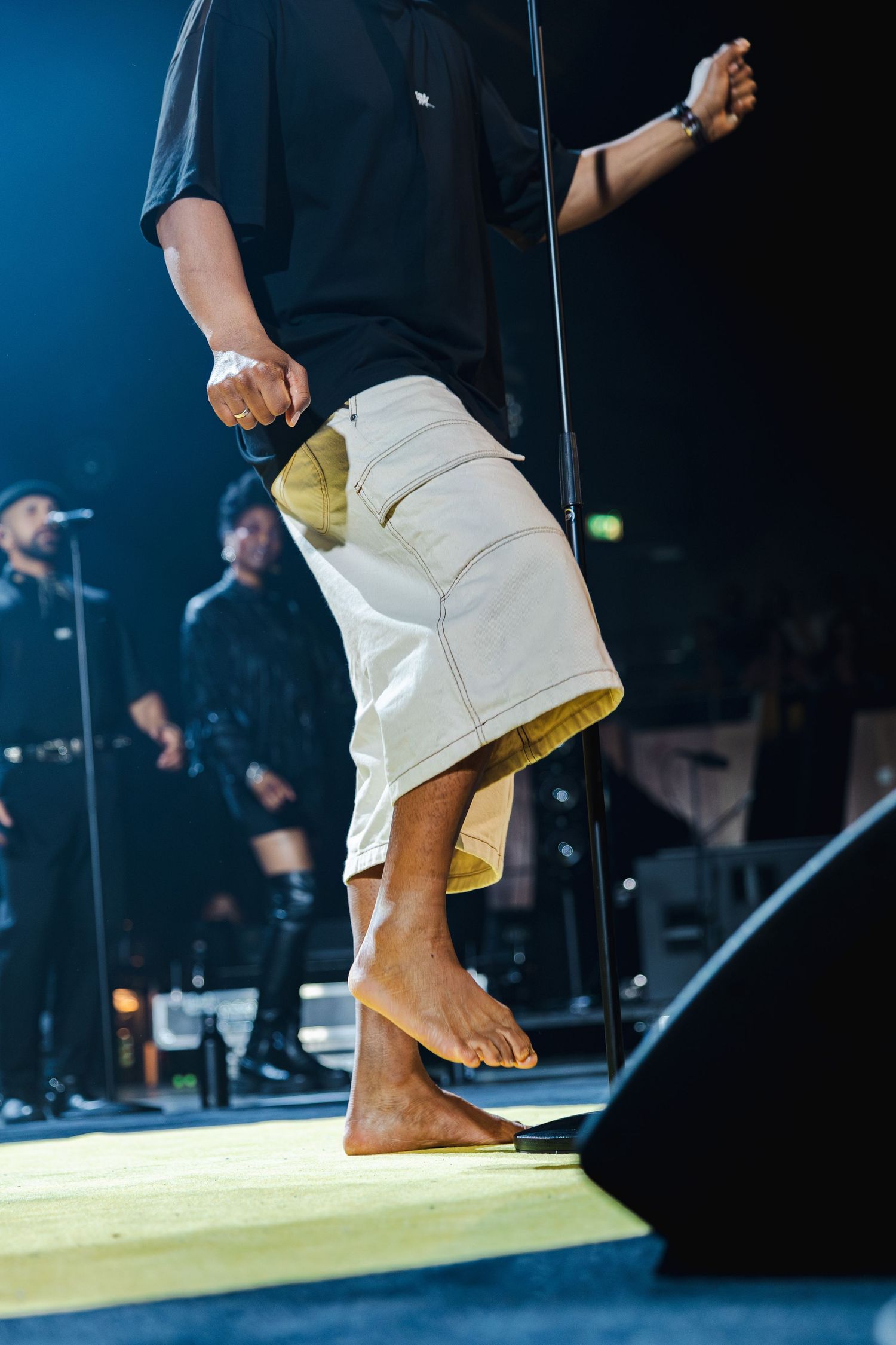 Close-up sequence of bare feet performing martial arts moves on a yellow platform against a dark background.