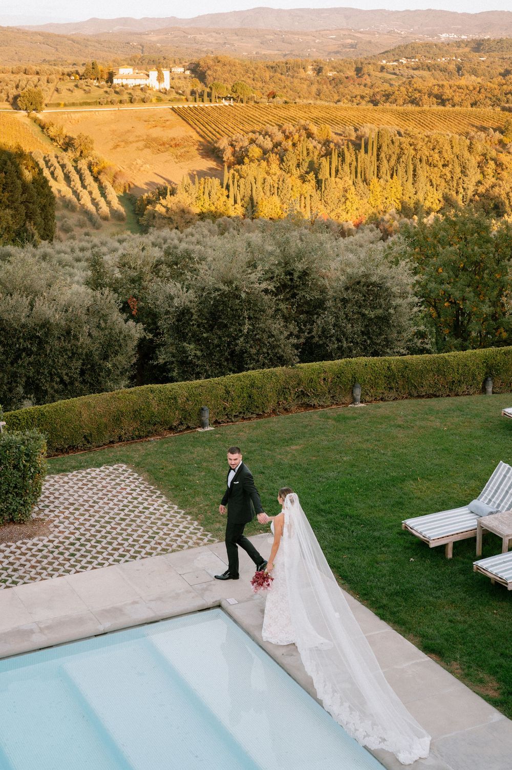 Scenic Tuscan countryside wedding venue with rolling hills, olive groves, and pool deck at golden hour.