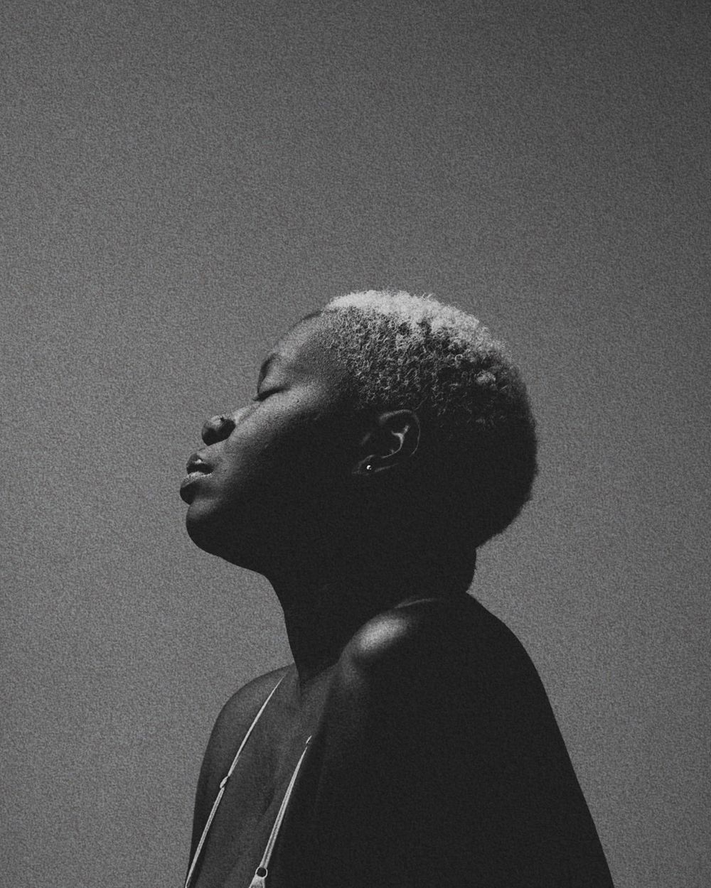 Black and white profile portrait with closed eyes and blonde short hair against a simple dark background.