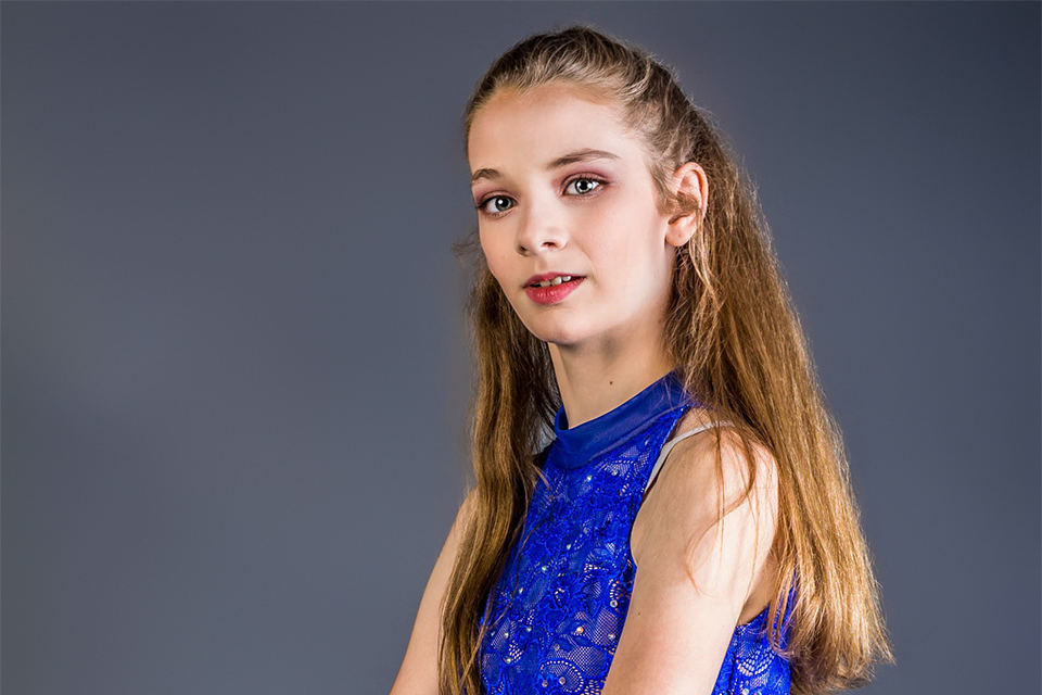 Figure in a royal blue sequined dress poses against a dark background.