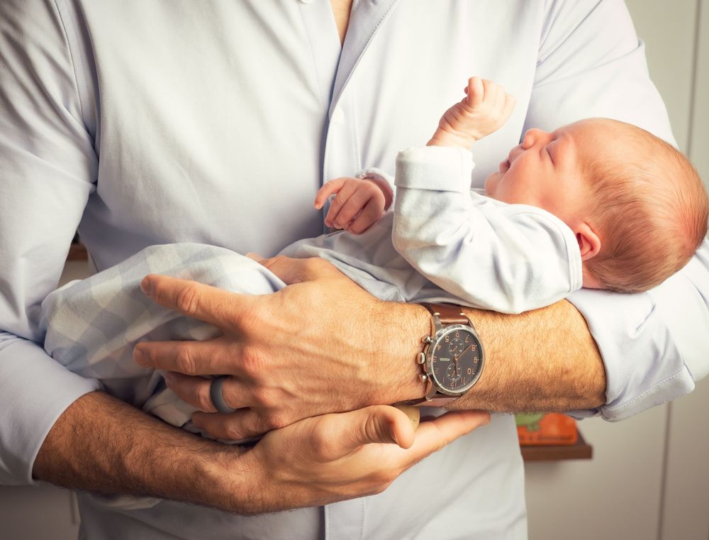 Series of tender moments holding a newborn baby in white clothing.