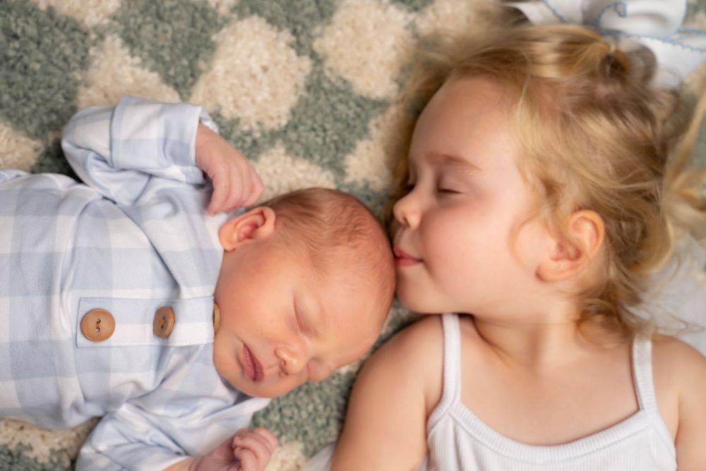 Children sleeping peacefully on patterned carpet in gentle light.
