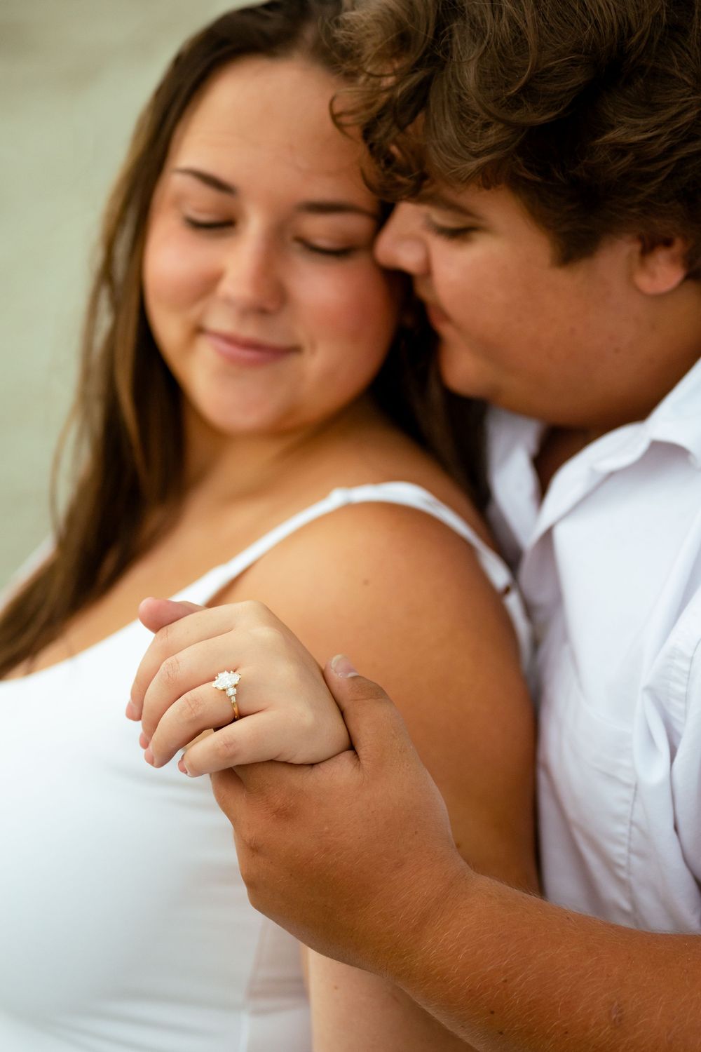 A romantic engagement photo series showing close-up shots of a couple embracing and displaying the ring.