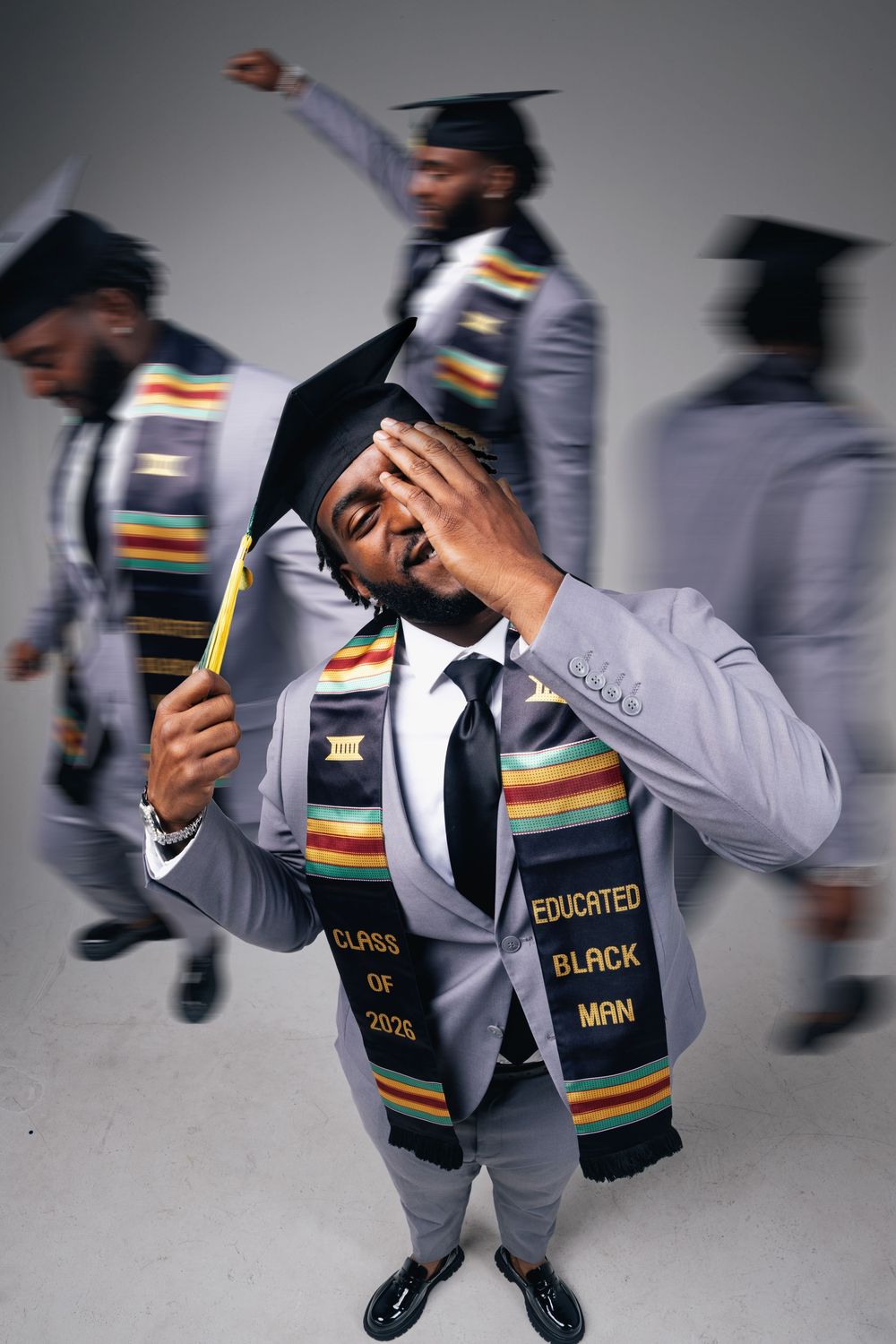 Graduate in gray suit wearing Educated Black Man stole and cap poses confidently in Class of 2020 graduation photo.