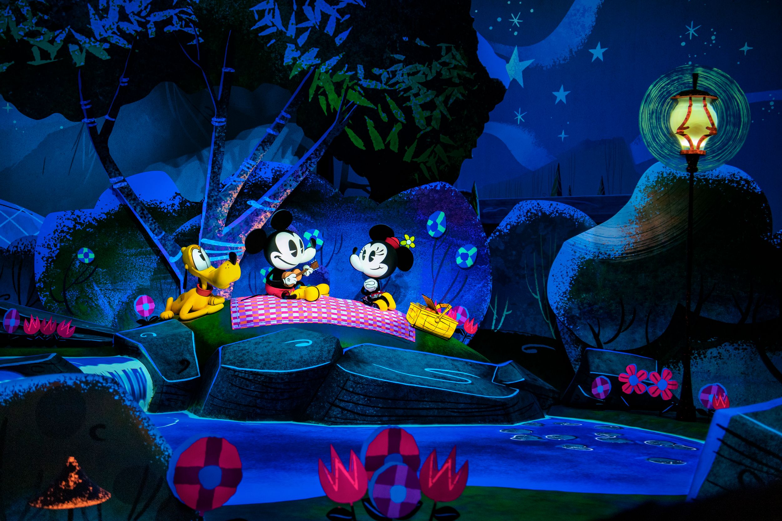 A colorful underwater theme park ride at night featuring illuminated decorative elements and neon lighting effects.