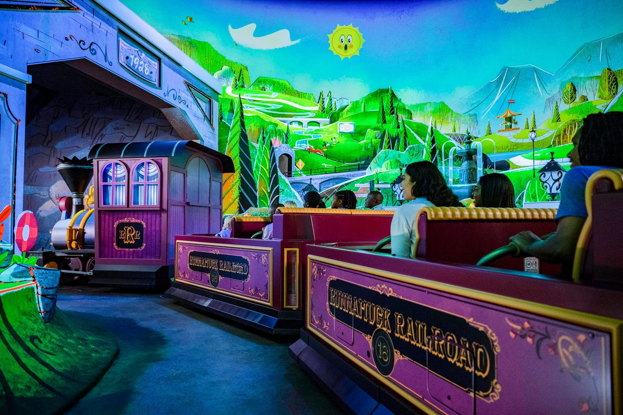 Colorful indoor theme park ride with vibrant neon lights and painted fantasy landscapes on display.