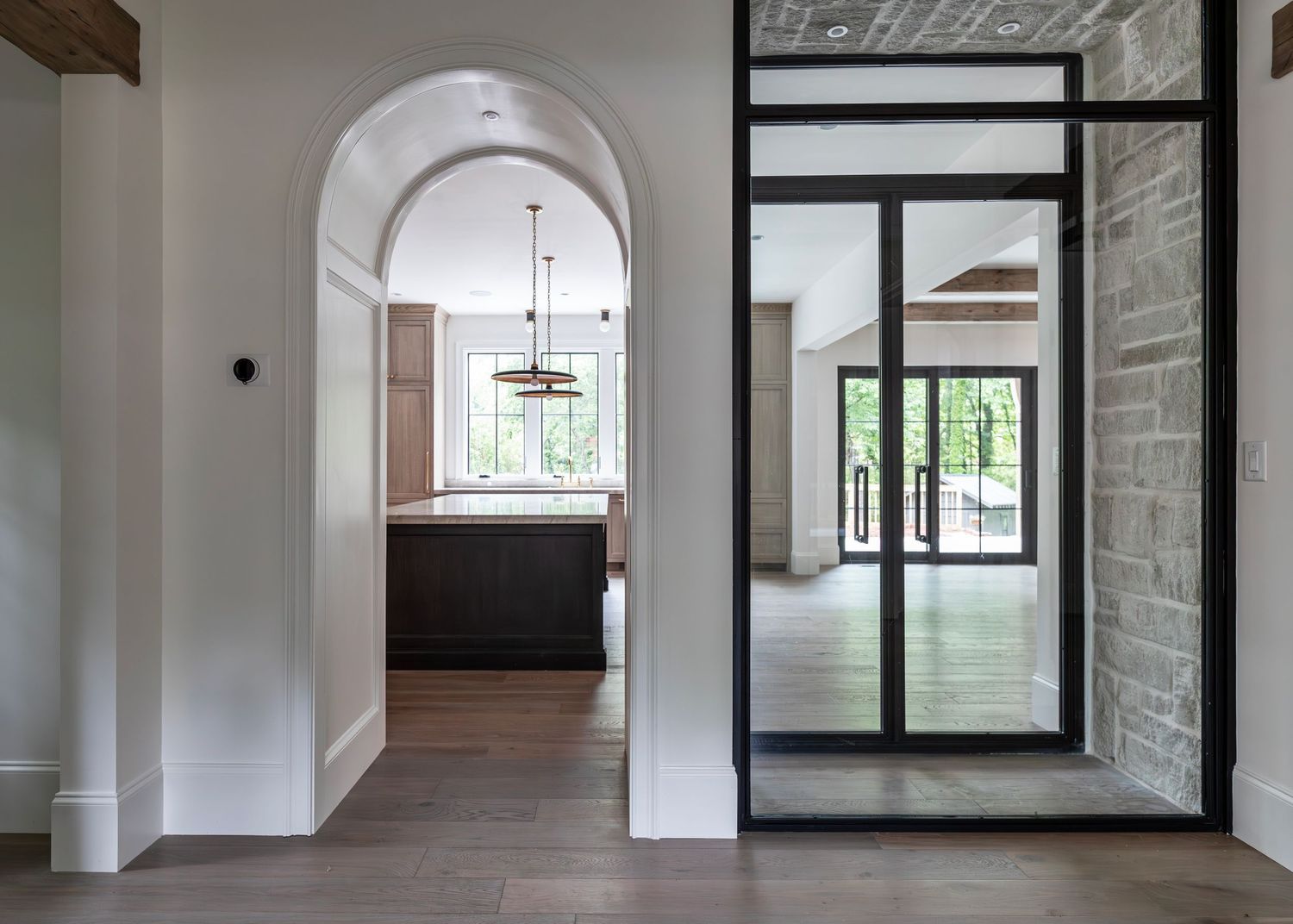Modern home interior with arched doorway and glass sliding door showcasing elegant architectural details and natural light.