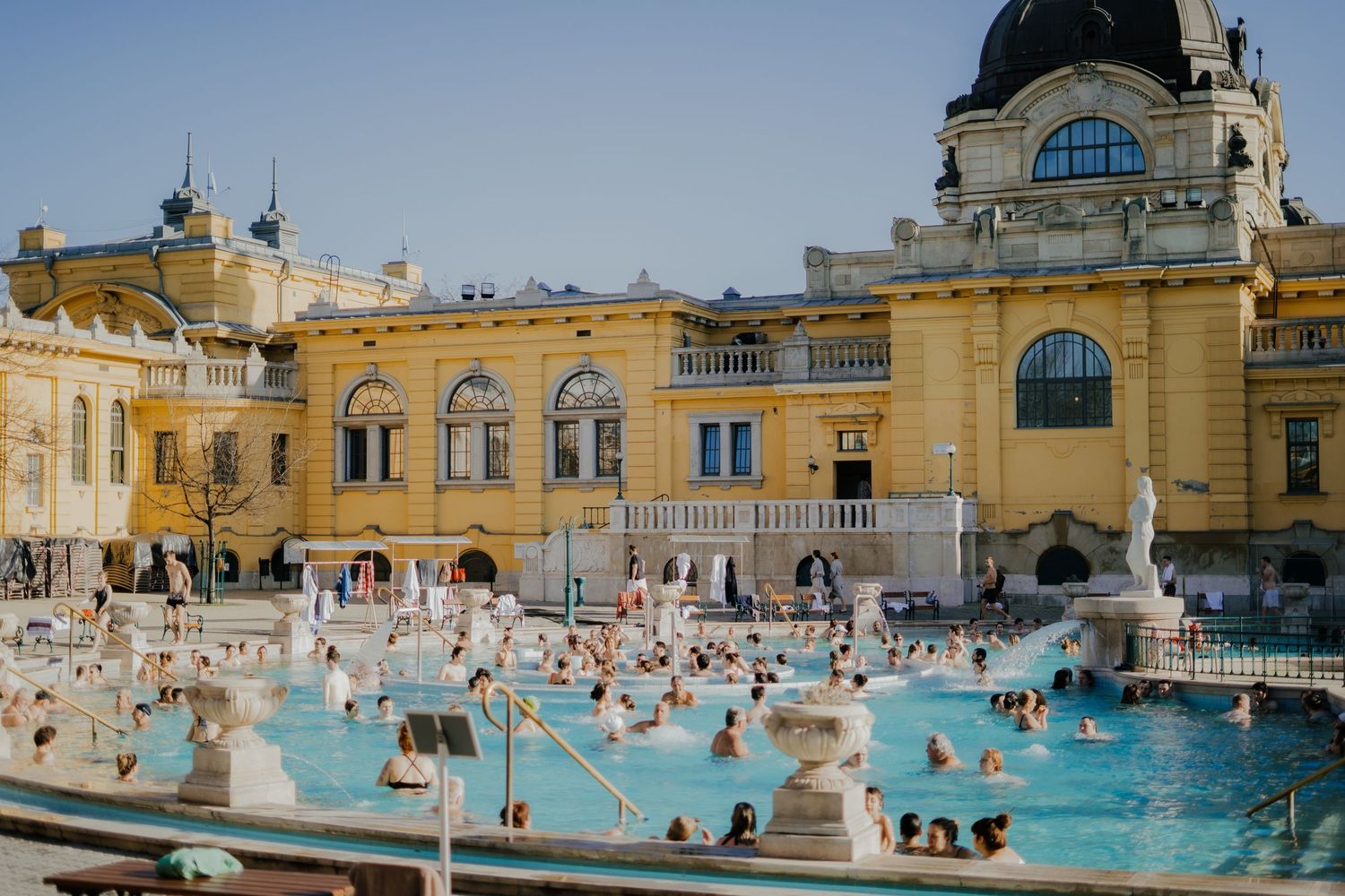 Visitors enjoying the thermal baths at the historic Szechenyi Bath complex in Budapest, Hungary on a sunny day.