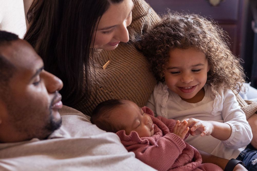 A family gathers around their newborn baby.