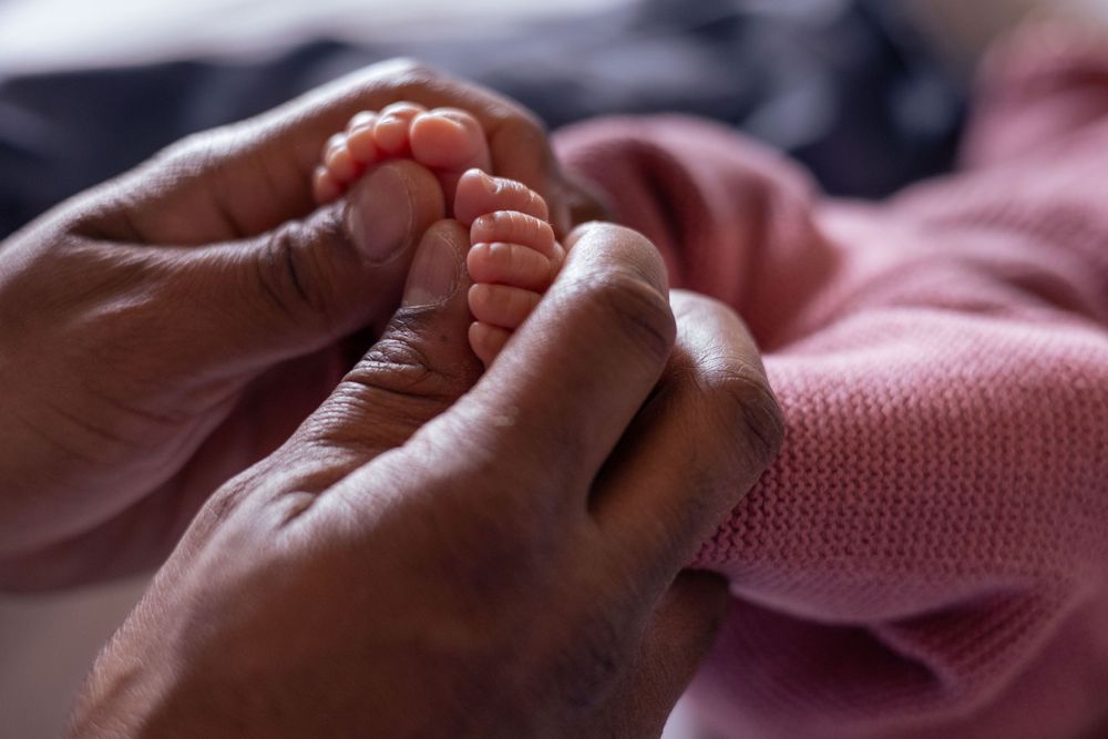 Dad holds his newborns tiny feet in his hands.
