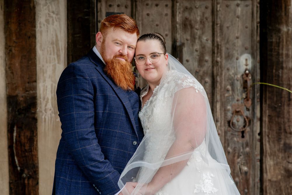 Newlyweds posing together in front of rustic wooden door.