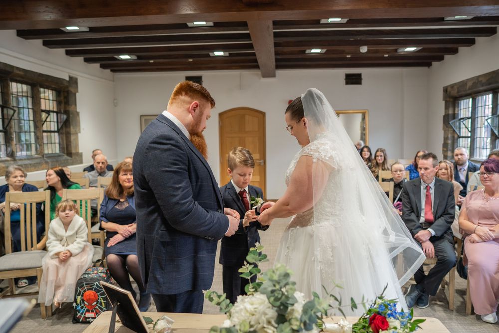 Wedding ceremony shows couple at the altar with guests seated in wooden chairs.
