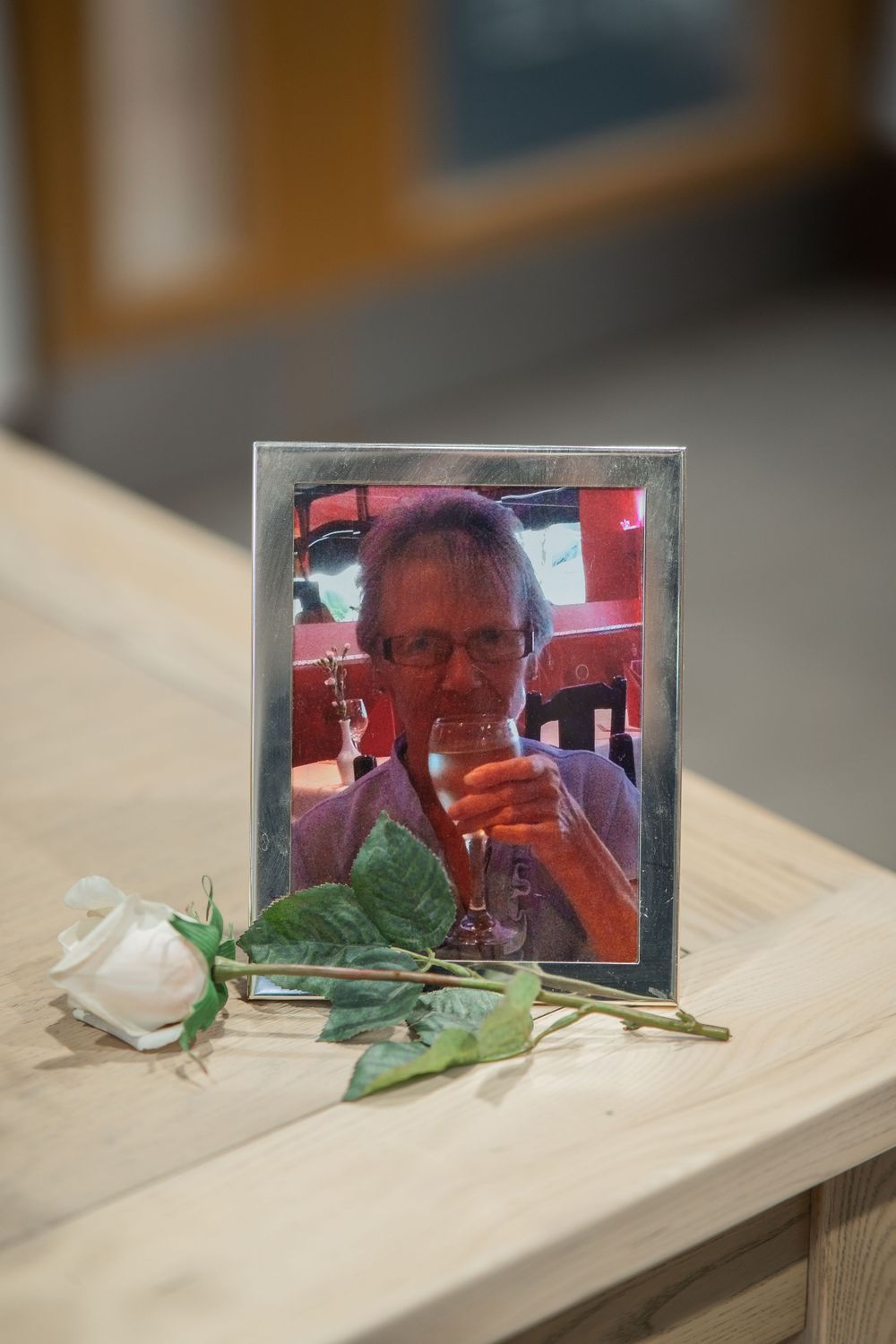 A framed photograph displayed on a light wooden surface with green leaves beside it.