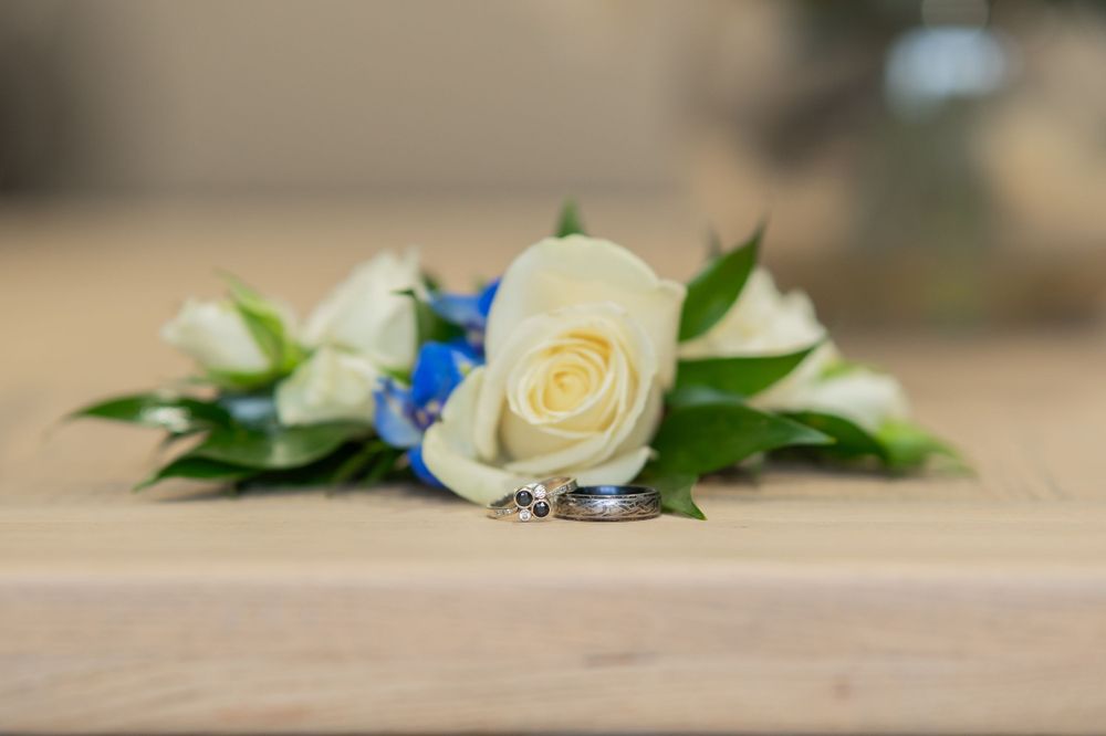 White rose and blue flower wedding decoration arrangement on wooden surface.