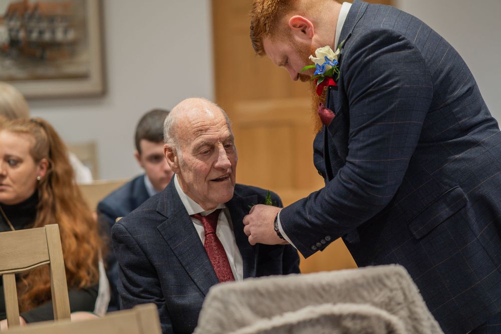 A boutonniere being pinned on a suited guest during a formal event.