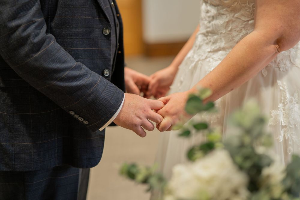Close-up view of hands clasped together during an intimate wedding ceremony moment.