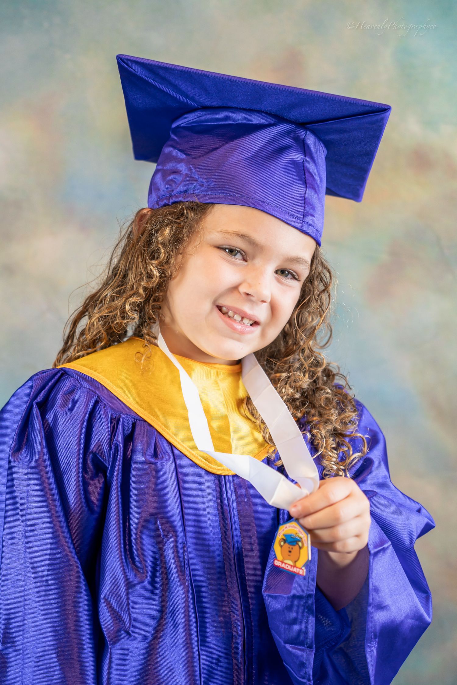 Graduate in blue cap and gown making peace sign during photo shoot.