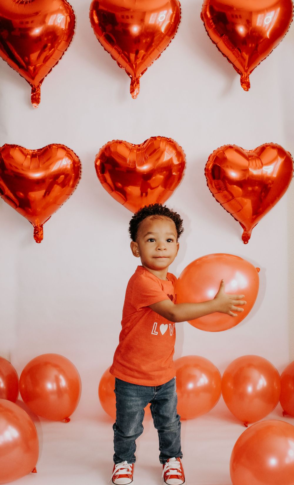 Festive Valentine's day photo setup with red heart balloons and orange decorations.