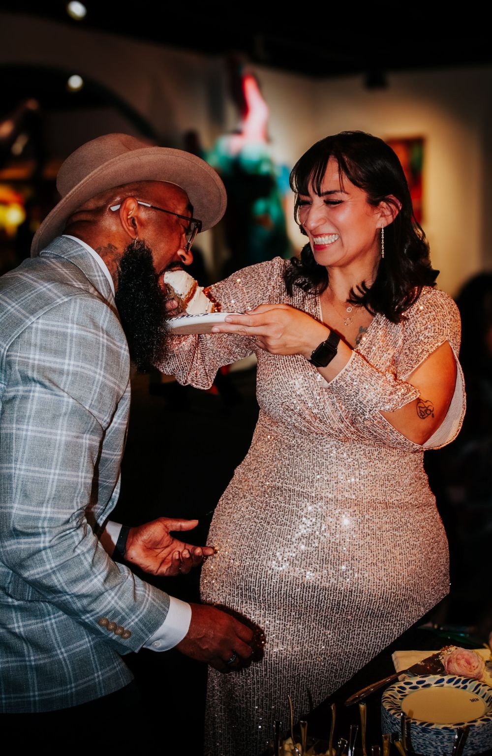 Couple dancing and laughing together, with woman in sparkly dress and man in casual attire.