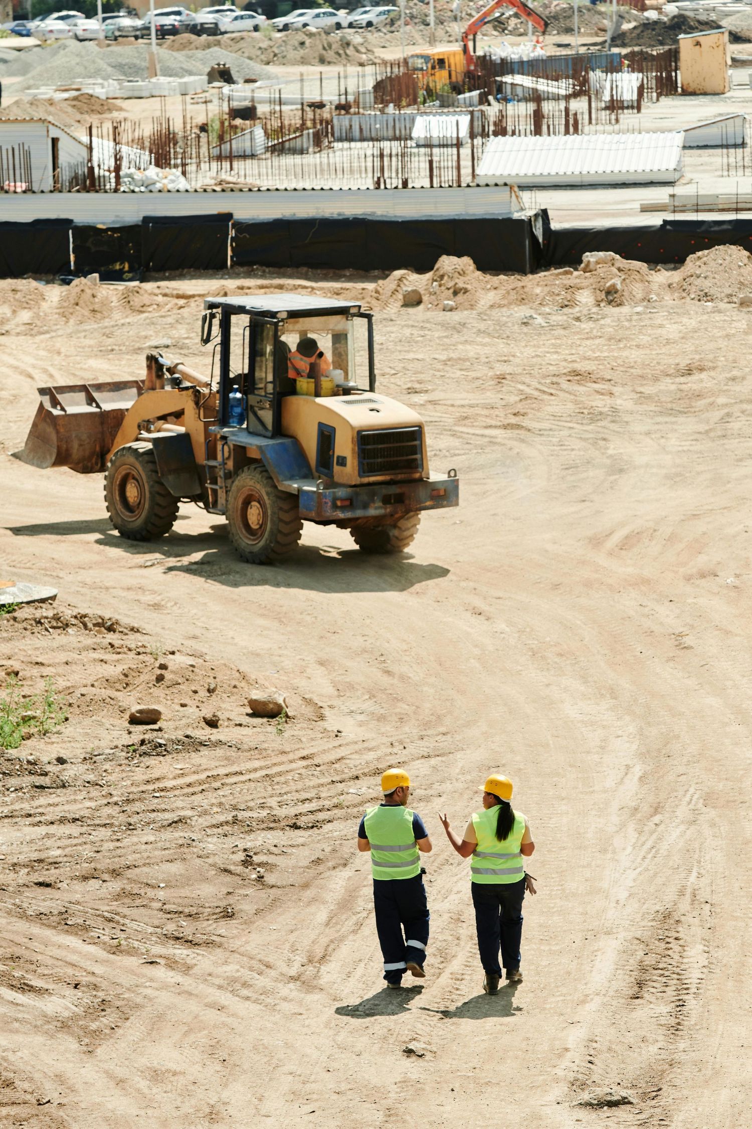 Construction site with workers in safety vests observing heavy equipment operation.