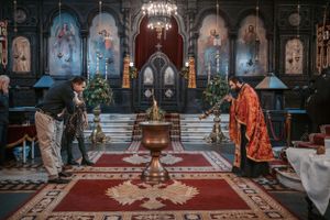 Panoramic view of Orthodox church interior with red carpets and ornate decorations during ceremony.