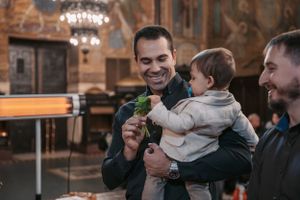 An intimate celebration in an ornately decorated church interior with a small child being held.