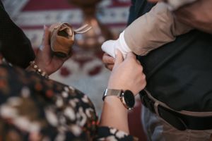 Close-up of hands adjusting clothing during a formal ceremony.