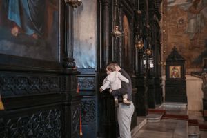 A tender moment in a church with decorative dark wood panels and religious artwork.