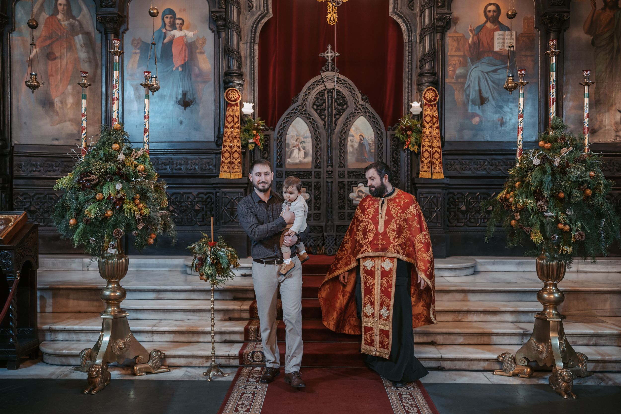 Religious ceremony in an ornately decorated church with floral arrangements and candles.