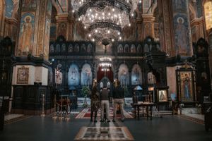 Interior view of an Orthodox church with ornate decorations, chandeliers and religious artwork.