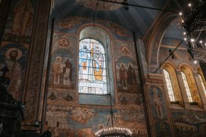 Interior of an ornate Orthodox church with beautiful frescoes, stained glass windows, and traditional architectural details.