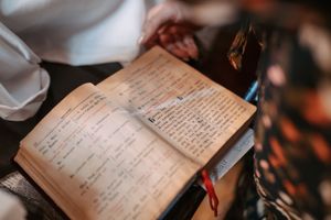 Ancient religious text or manuscript book with handwritten script shown during church ceremony.