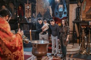 Traditional Orthodox baptism ceremony taking place in a beautifully decorated church setting.