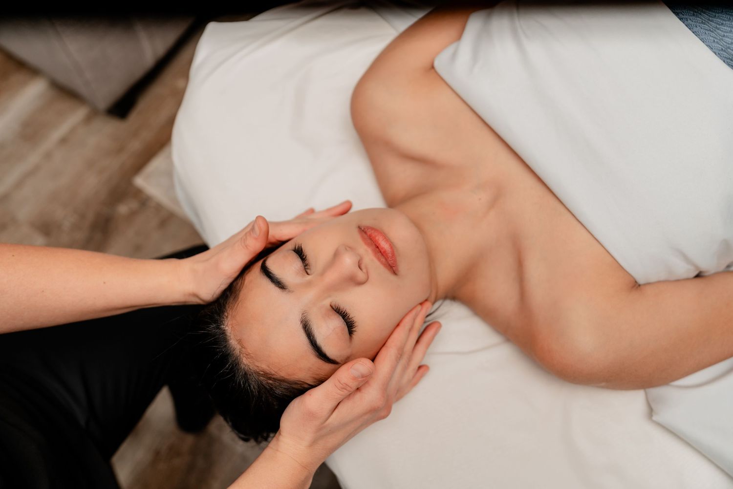 Client receiving a relaxing facial massage during a spa treatment on a white massage table.