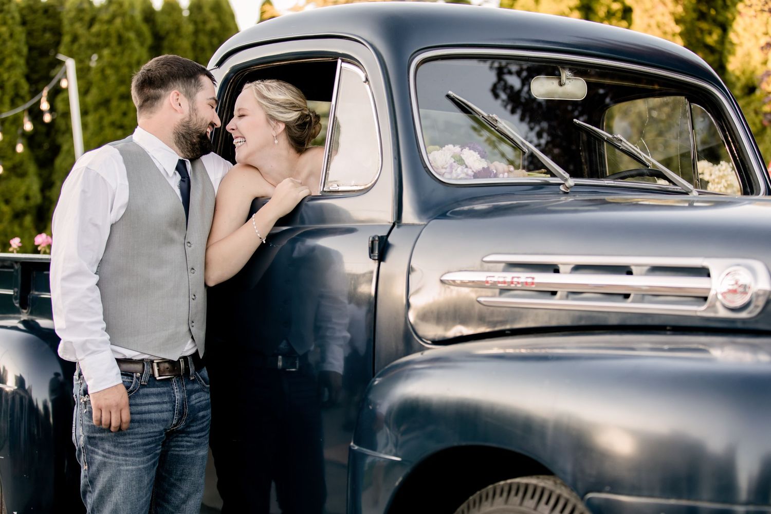 Romantic couple posing beside a vintage blue pickup truck during a countryside photoshoot.