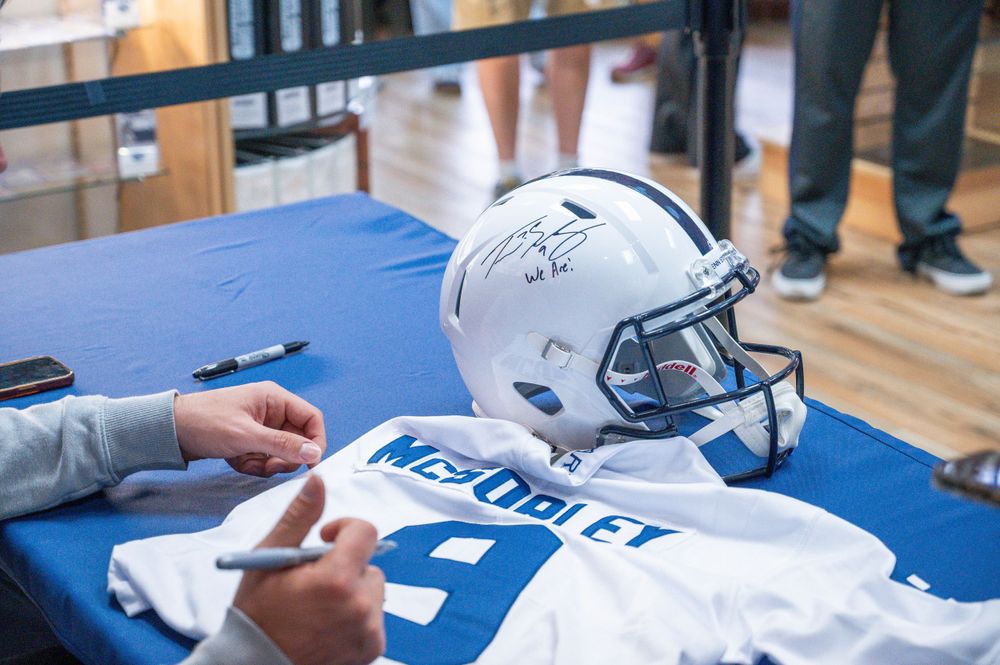 A Dallas Cowboys football helmet and jersey displayed on a blue signing table during an autograph session.