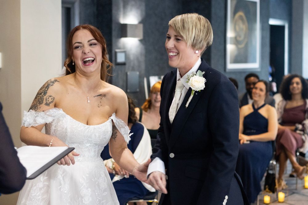 Brides both laughing and happy on their wedding day