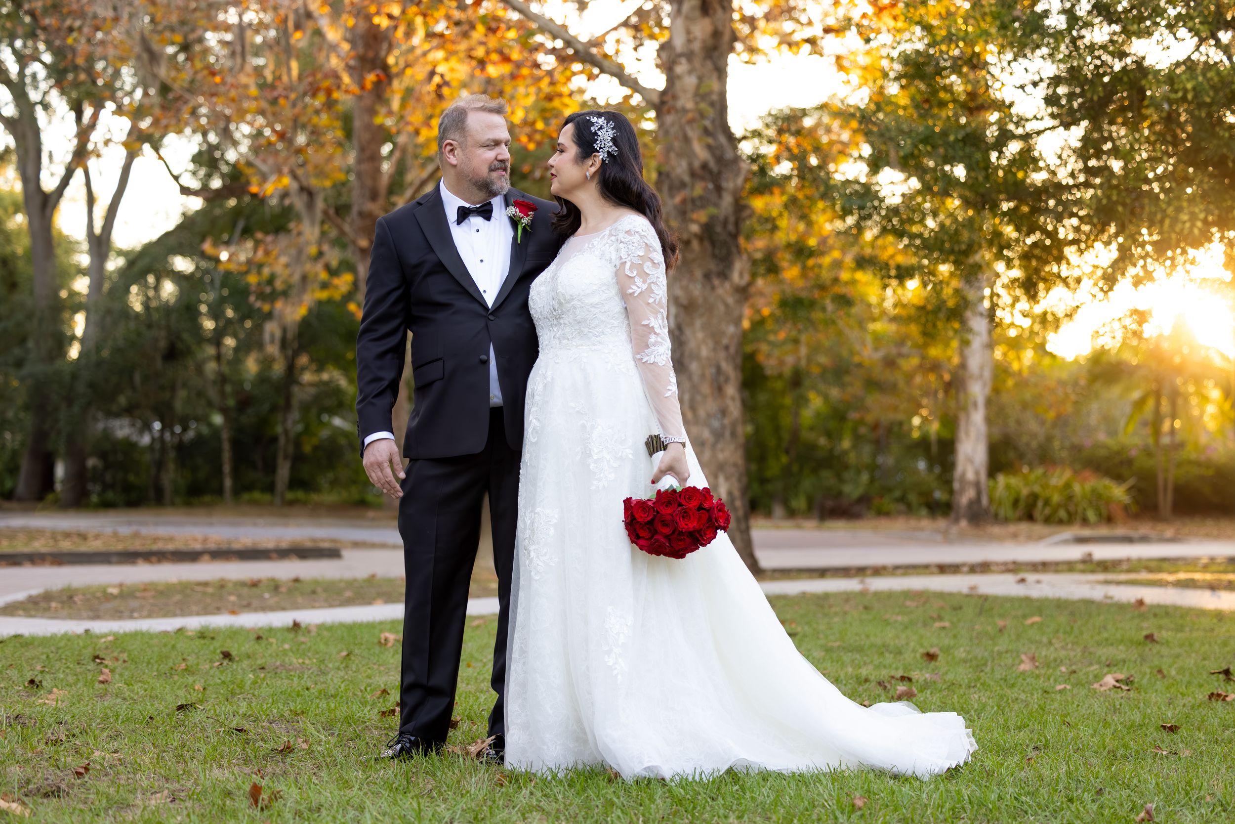 A romantic wedding couple stands together on grass during golden hour at Mead Botanical Gardens in Orlando.