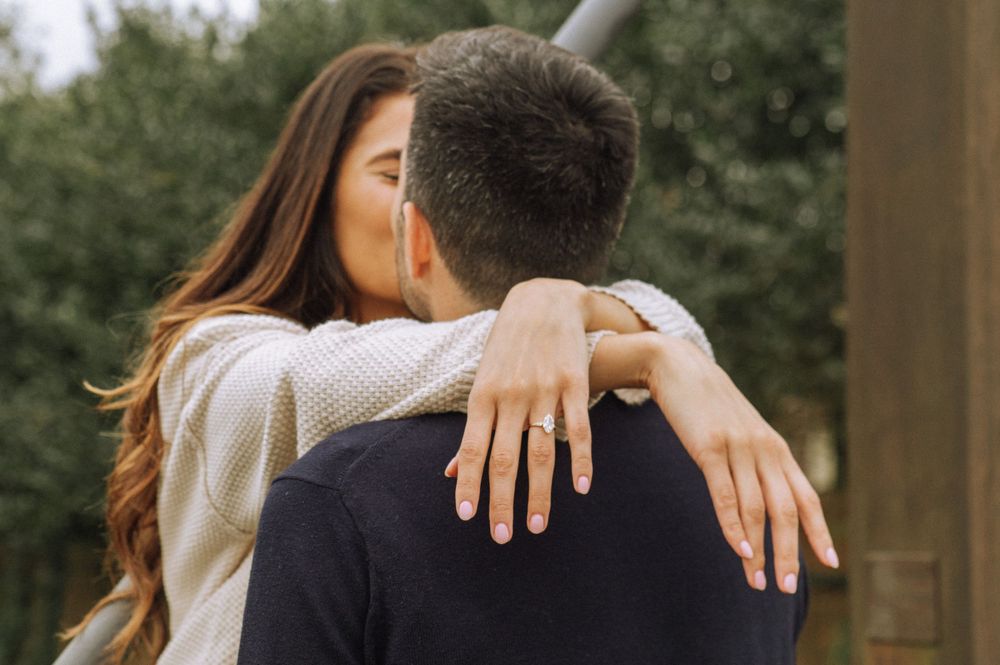 An intimate embrace captured from behind showing hands wrapped around shoulders.