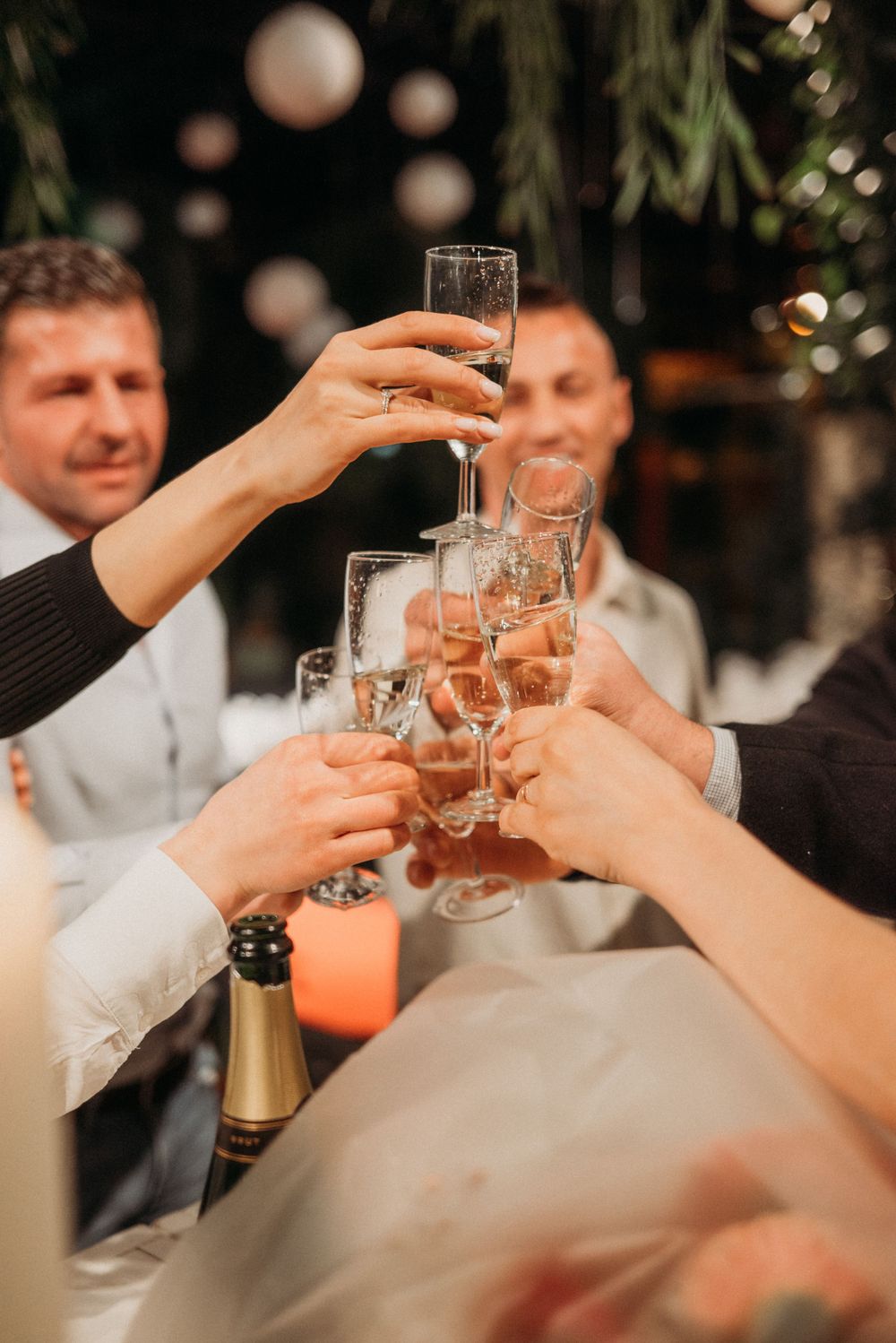 Hands raising champagne glasses for a celebratory toast at an evening event.