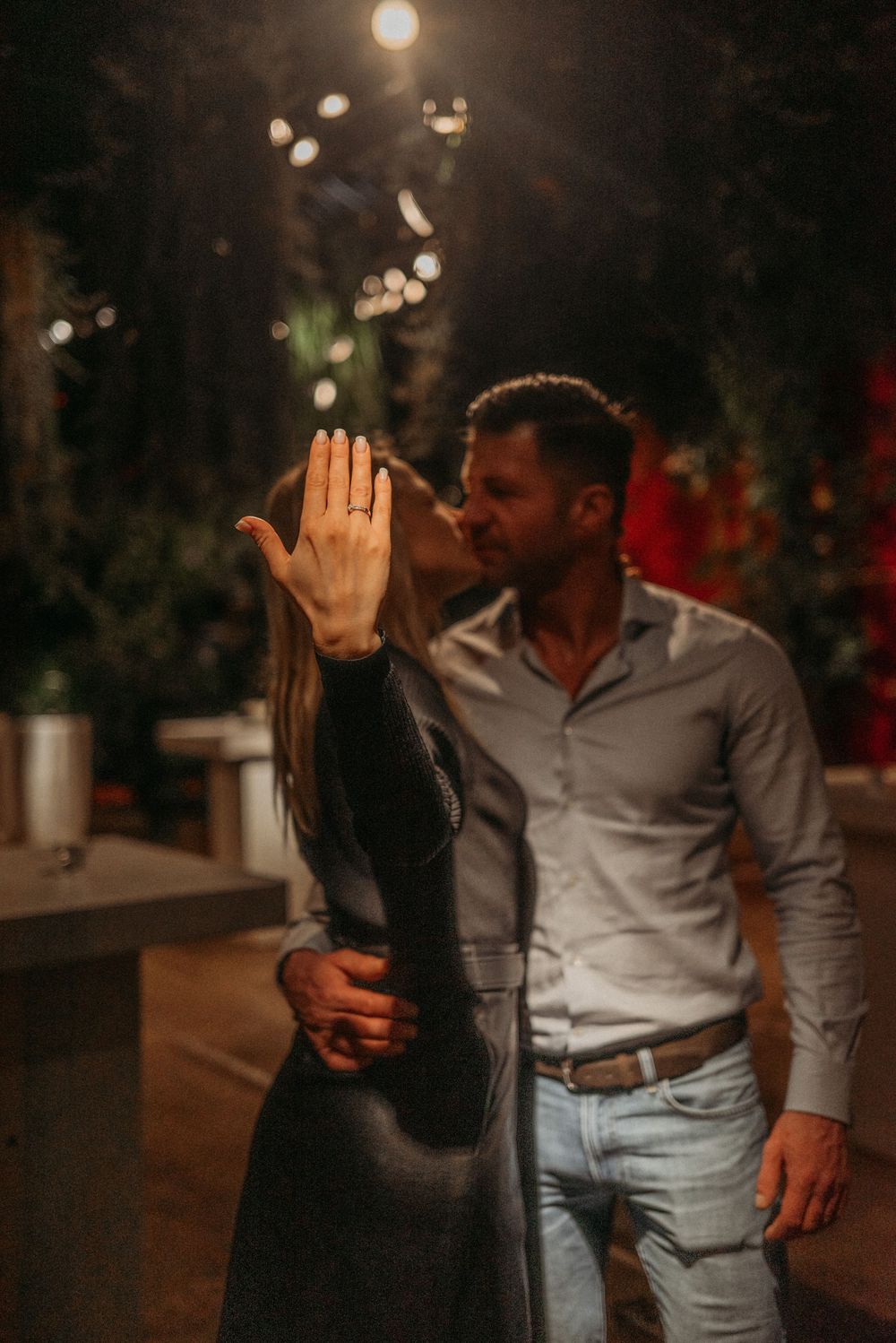 A romantic couple sharing a high-five moment at a dimly lit outdoor venue.